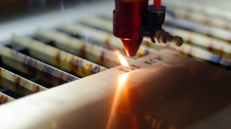 A close-up of a laser engraving machine cutting characters into metal.