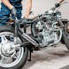 A mechanic working on a motorcycle, partially disassembled